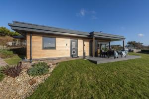 a small wooden house with a patio and grass at Wavelength in St. Agnes 