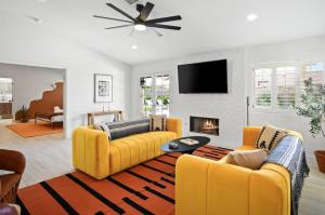 sala de estar con 2 sofás amarillos y chimenea en La Reina Inn Swim Club, en Bermuda Dunes