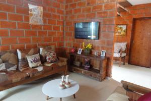 a living room with a brick wall with a couch and a tv at Chácara Família Batista in Mairiporã