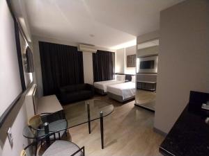 um quarto de hotel com uma cama e uma sala de estar em Royal Golden Hotel - Savassi em Belo Horizonte
