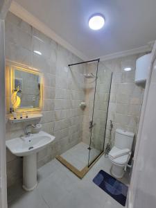 een badkamer met een douche, een wastafel en een toilet bij Glamour Pyramids Hotel in Caïro