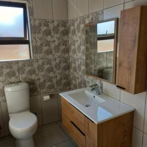 a bathroom with a toilet and a sink and a mirror at Serene Cottage in Francistown