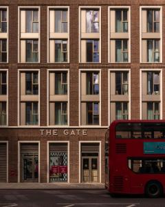 a red double decker bus parked in front of a building at The Gate London City in London
