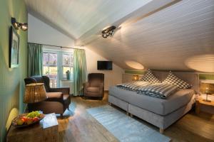 um quarto com uma cama, um sofá e uma cadeira em Der Landhof em Oberstdorf