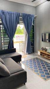 ein Wohnzimmer mit einem Sofa und einem blauen Vorhang in der Unterkunft Homestay Mohd Aizri Bukit Gading in Distrikt Tanah Merah