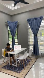 丹那美拉Homestay Mohd Aizri Bukit Gading的坐在桌子上,拿着盒子的人