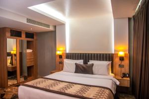 una stanza d'albergo con un letto e uno specchio di Golden Tulip Lekki a Lekki