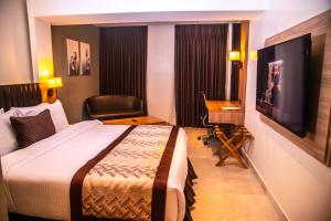 una camera d'albergo con un letto, una scrivania e una televisione di Golden Tulip Lekki a Lekki