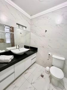 ein weißes Bad mit einem WC und einem Waschbecken in der Unterkunft Moderno Vista Mar - AR | Piscina | Vaga Garagem in São Vicente