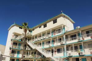 un bâtiment avec des balcons blancs et un palmier dans l'établissement Hotel Guillen, à Tijuana