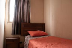 um quarto com uma cama com uma almofada vermelha em Amplio departamento amoblado a pasos del Movistar Arena, ubicado en Nataniel Cox em Santiago