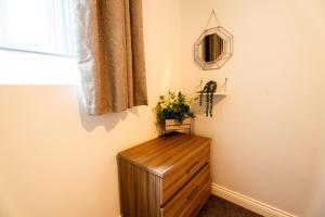 a wooden dresser in a room with a window at Converted Chapel Swansea | King Bed | Sleeps 4. in Swansea