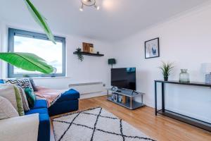 ein Wohnzimmer mit einem blauen Sofa und einem TV in der Unterkunft Cohost Partners - Elegant Escape Broadway in Birmingham
