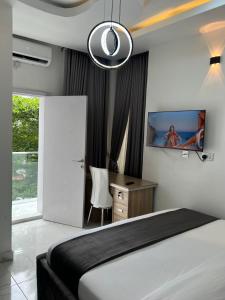a bedroom with a bed and a desk and a tv at HighX Hotels in Port Harcourt