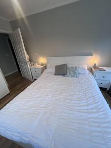 uma grande cama branca num quarto com duas mesas de cabeceira em The Coastal Apartment em Dublin