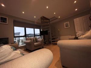uma sala de estar com um sofá, uma cadeira e uma janela em The Coastal Apartment em Dublin
