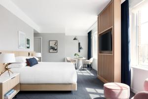 a bedroom with a white bed and a tv at Kimpton - The Forum Hotel by IHG in Charlottesville