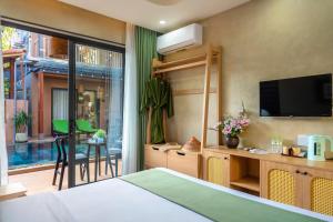 a bedroom with a bed and a tv and a balcony at The Linh Seaside Villa Hoi An in Hoi An