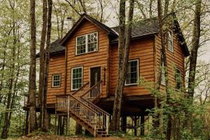 uma cabana de madeira na floresta com uma escada em Treehouse in Maine woods- The Grand Oak em North Lovell