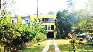 a yellow building with a garden in front of it at AYM Yoga Resort Arambol GOA in Arambol