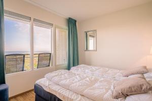 ein Schlafzimmer mit einem Bett und einem großen Fenster in der Unterkunft Appartementencomplex Juliana 102 in De Koog