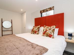 Un dormitorio con una gran cama blanca con cabecero rojo. en The Gardener's Retreat, en Penrith