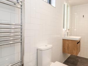 Un baño blanco con inodoro y lavabo. en The Gardener's Retreat, en Penrith