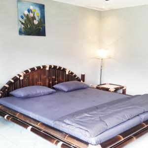 um quarto com uma cama grande e uma cabeceira em madeira em Villa Situ Jampang Campsite em Megamendung