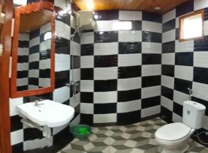 uma casa de banho com uma parede xadrez em preto e branco em Villa Situ Jampang Campsite em Megamendung