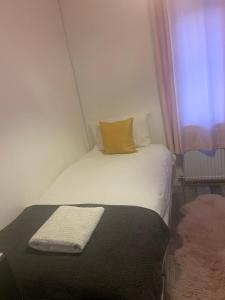 ein kleines Schlafzimmer mit einem weißen Bett und einem gelben Kissen in der Unterkunft Cheltenham ,Gloucestershire,United Kingdom 