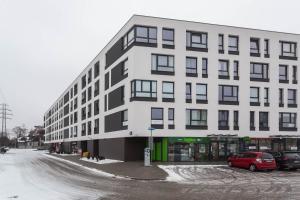 un edificio bianco con un'auto rossa parcheggiata di fronte di Enjoy! Ursynów a Varsavia