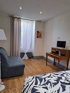 a bedroom with a bed and a desk with a tv at Au P'tit Gueul'ton in Les Aix-dʼAngillon