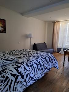 um quarto com uma cama preta e branca e uma cadeira em Au P'tit Gueul'ton em Les Aix-dʼAngillon