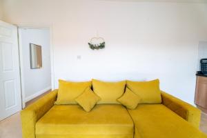 a yellow couch with pillows in a living room at Cozy Urban Retreat - Modern 1BR - Free Parking in Bristol