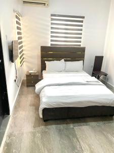 1 dormitorio con 1 cama grande con sábanas blancas en CHRIS SPORSHE en Abuja