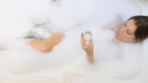 a woman in a bath tub holding a alarm clock at Estalagem Coração Da Mata in Gramado