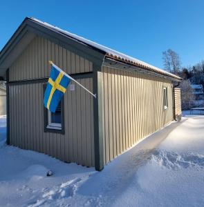una bandiera appesa sul fianco di un edificio nella neve di Sjöställe Gudö, annexet a Vendelsö