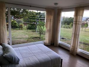 a bedroom with a bed and two large windows at Apricot Hosteria in Quito