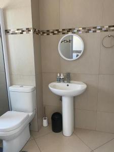 a bathroom with a toilet and a sink and a mirror at Makyle's Selfcatering Apartment in Windhoek