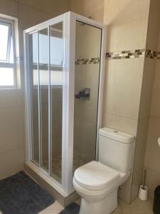 a bathroom with a white toilet and a shower at Makyle's Selfcatering Apartment in Windhoek