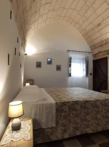 um quarto com uma cama e uma mesa com um candeeiro em Masseria Salentina Costarella em Borgagne