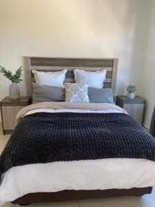 un grande letto con coperta nera e cuscini di Makyle's Selfcatering Apartment a Windhoek