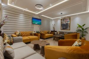 a living room with couches and a flat screen tv at Hôtel Des Lilas in Oujda