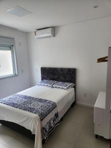 um quarto com uma cama grande num quarto branco em Recanto Brisa e Mar em Palhoça