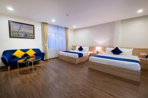 a hotel room with two beds and a couch at Sandals Star Hotel in Ðưc Trọng