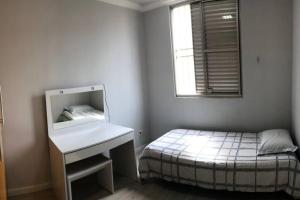 a bedroom with a bed and a sink and a mirror at Apartamento completo, com excelente localização in Americana
