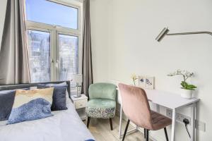 um quarto com uma cama, uma secretária e uma cadeira em The Finsbury Deluxe Apartments em Londres