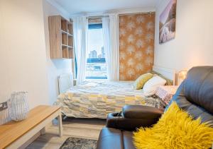 a bedroom with a bed and a couch and a window at Canary Wharf Skyline Sanctuary London in London