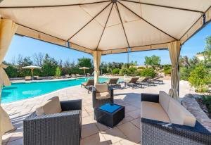 麗都馬里尼的住宿－Masseria Tenuta Specolizzi，一个带大遮阳伞的庭院,毗邻一个游泳池
