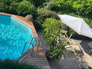 ein Sonnenschirm und Stühle neben einem Pool in der Unterkunft Amore a prima vista b&b in Campiglia Marittima